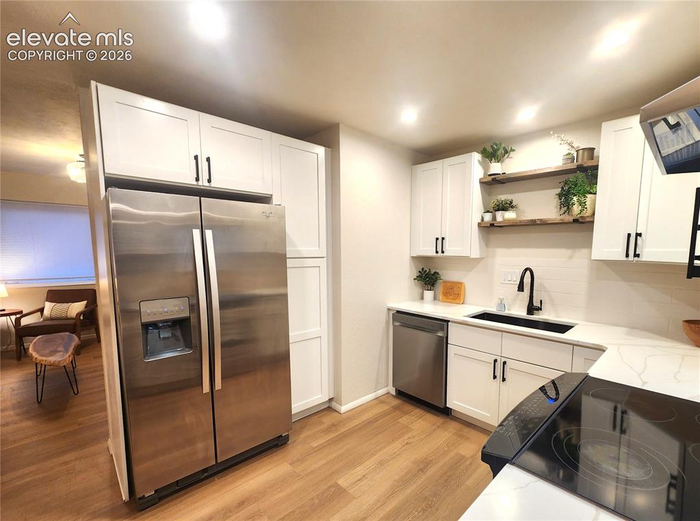 Image 4 of 18: White shaker cabinetry with matte black hardware, quartz countertops, stain