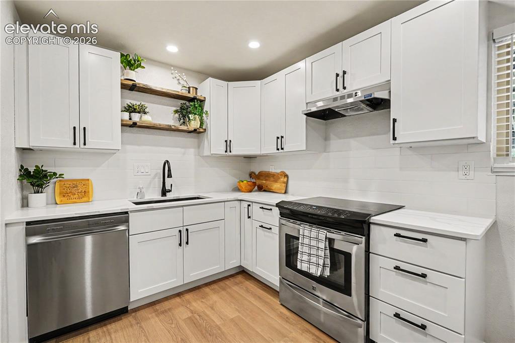 Image 5 of 22: Contemporary kitchen featuring white shaker cabinetry with matte black hard