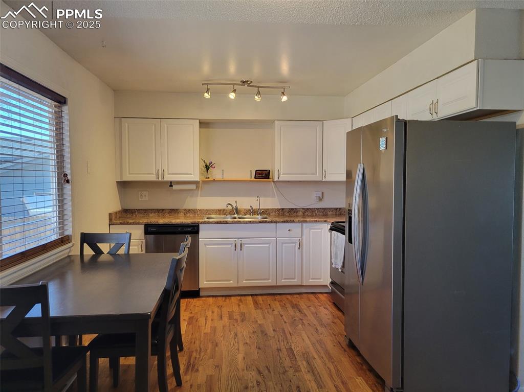 Image 11 of 43: Kitchen featuring stainless steel appliances, white cabinetry, wood floorin
