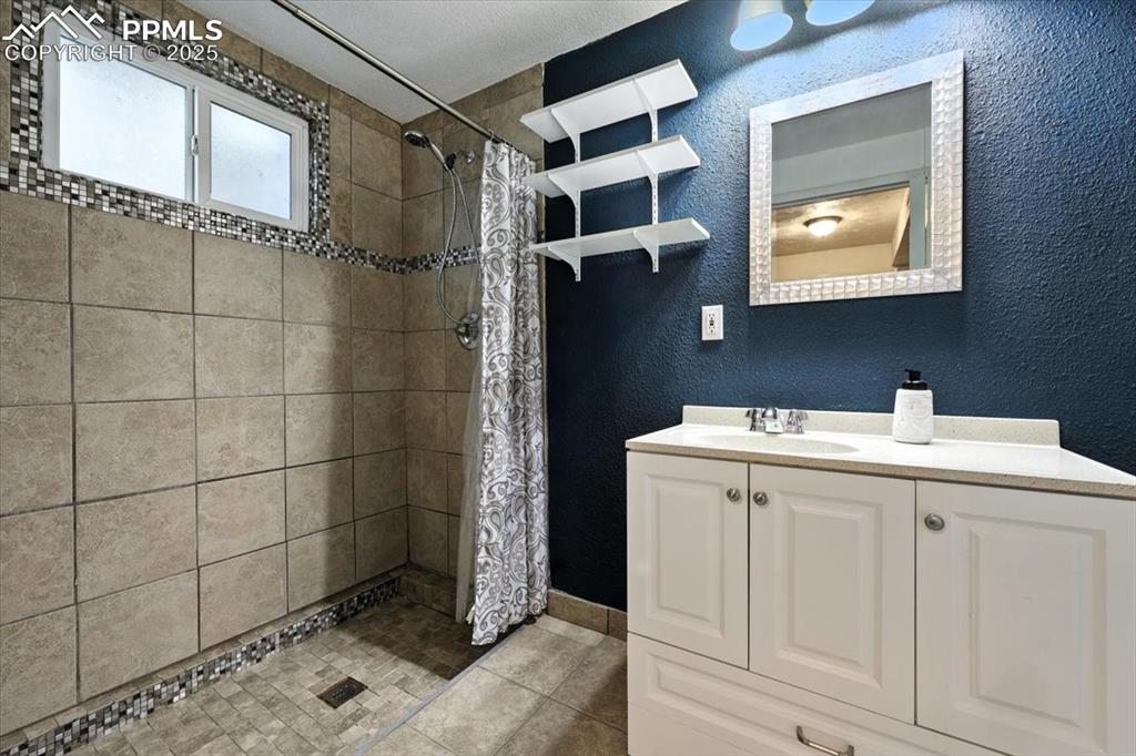 Image 33 of 43: Basement Shower Bathroom with vanity, mirrored medicine cabinet and tiled s