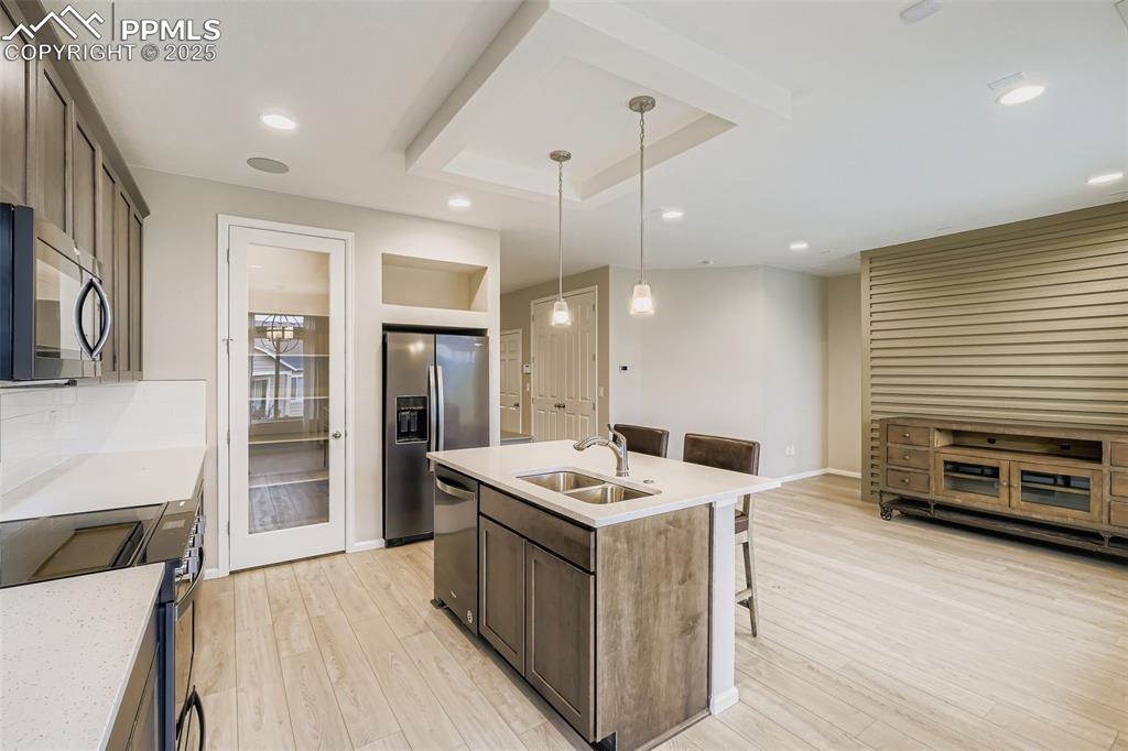 Image 10 of 28: Kitchen with a breakfast bar, dark brown cabinetry, decorative light fixtur