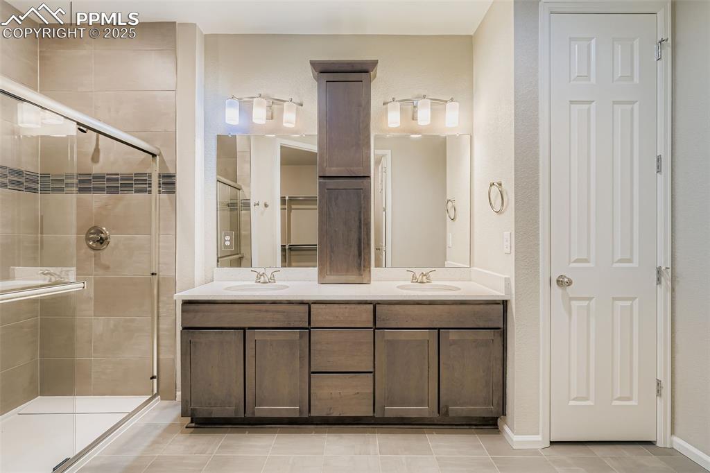 Image 16 of 28: Bathroom with a shower stall, double vanity, a closet, light tile patterned