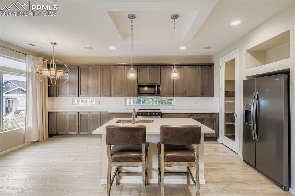 Image 2 of 28: Kitchen with a tray ceiling, stainless steel appliances, decorative light f