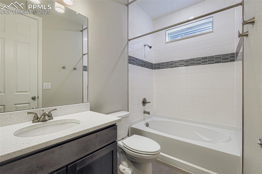 Image 20 of 28: Full bath featuring a textured wall, shower combination, vanity, and tile