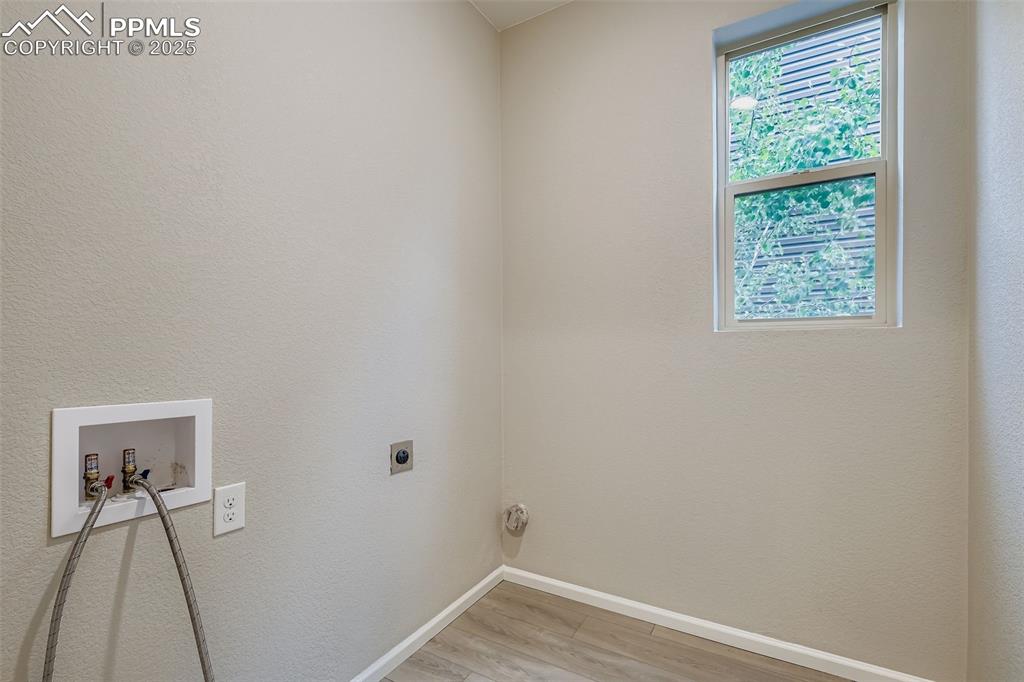Image 21 of 28: Laundry room featuring wood finished floors, a textured wall, hookup for a