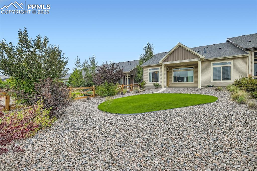 Image 25 of 28: Back of property featuring a shingled roof, a lawn, and board and batten si