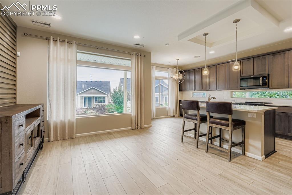 Image 3 of 28: Kitchen with a kitchen breakfast bar, hanging light fixtures, a center isla