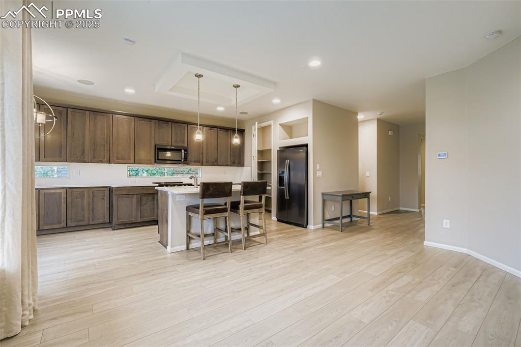 Image 5 of 28: Kitchen featuring a breakfast bar area, a kitchen island, hanging light fix