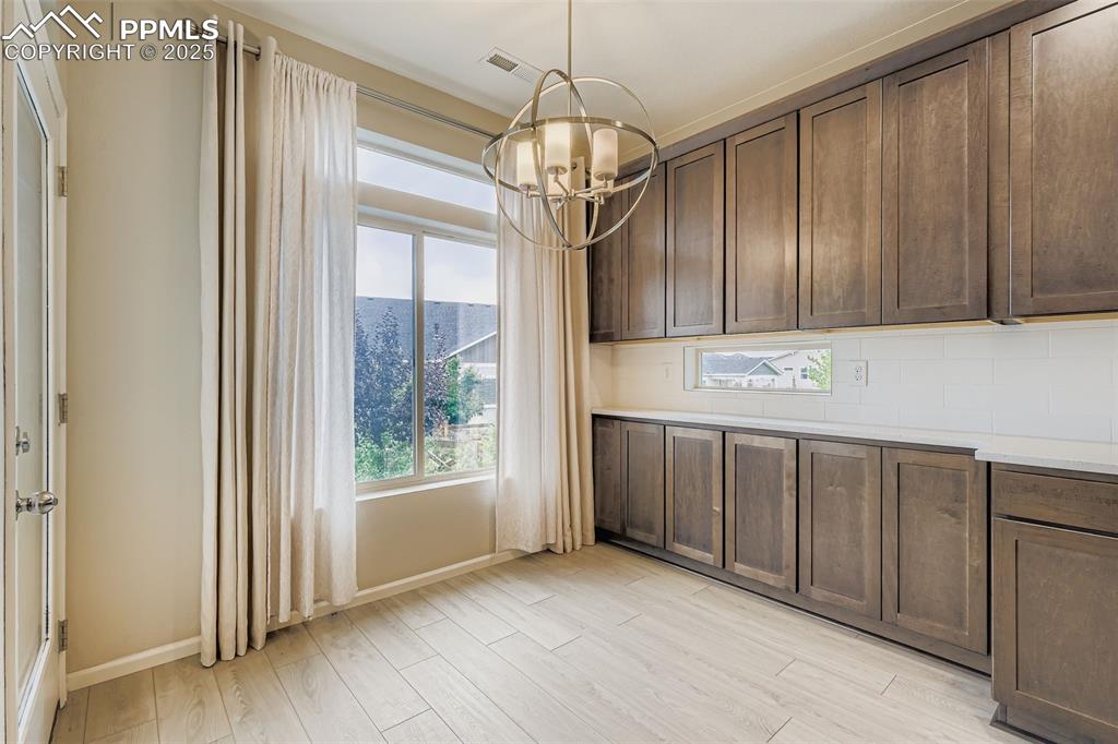 Image 6 of 28: Unfurnished dining area featuring light wood-style flooring and a chandelie