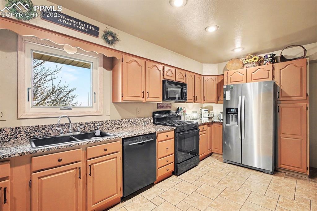 Image 10 of 34: Kitchen featuring black appliances, light stone countertops, and recessed l