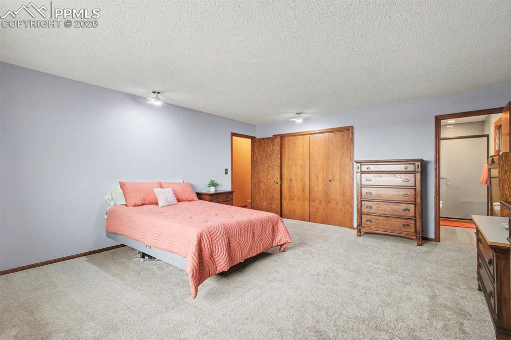 Image 13 of 34: Bedroom featuring a closet, light colored carpet, a textured ceiling, and a