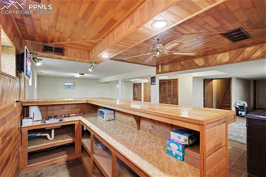 Image 20 of 34: Kitchen featuring butcher block countertops, wooden ceiling, a ceiling fan,