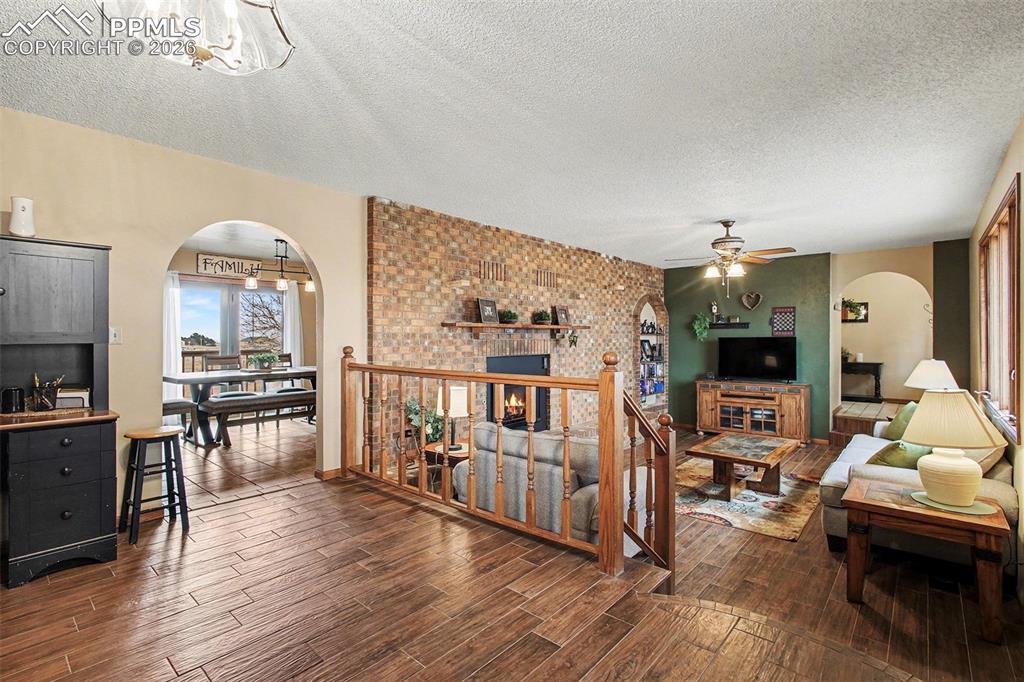 Image 6 of 34: Living room featuring arched walkways, a textured ceiling, wood finish floo