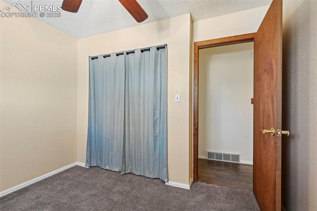 Image 11 of 27: This room features neutral-toned walls, grey carpet, and a ceiling fan with