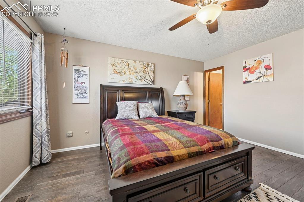 Image 14 of 27: This room features wood-look flooring, a ceiling fan, and a window with bli