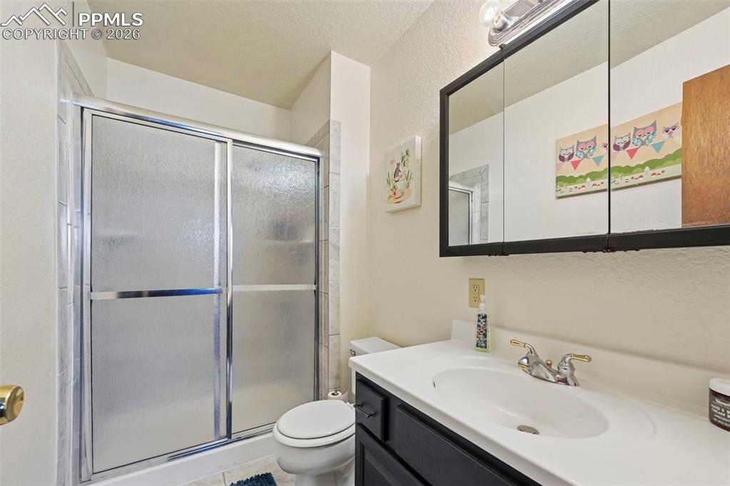 Image 15 of 27: Bathroom featuring a shower with sliding doors, a vanity with a white count