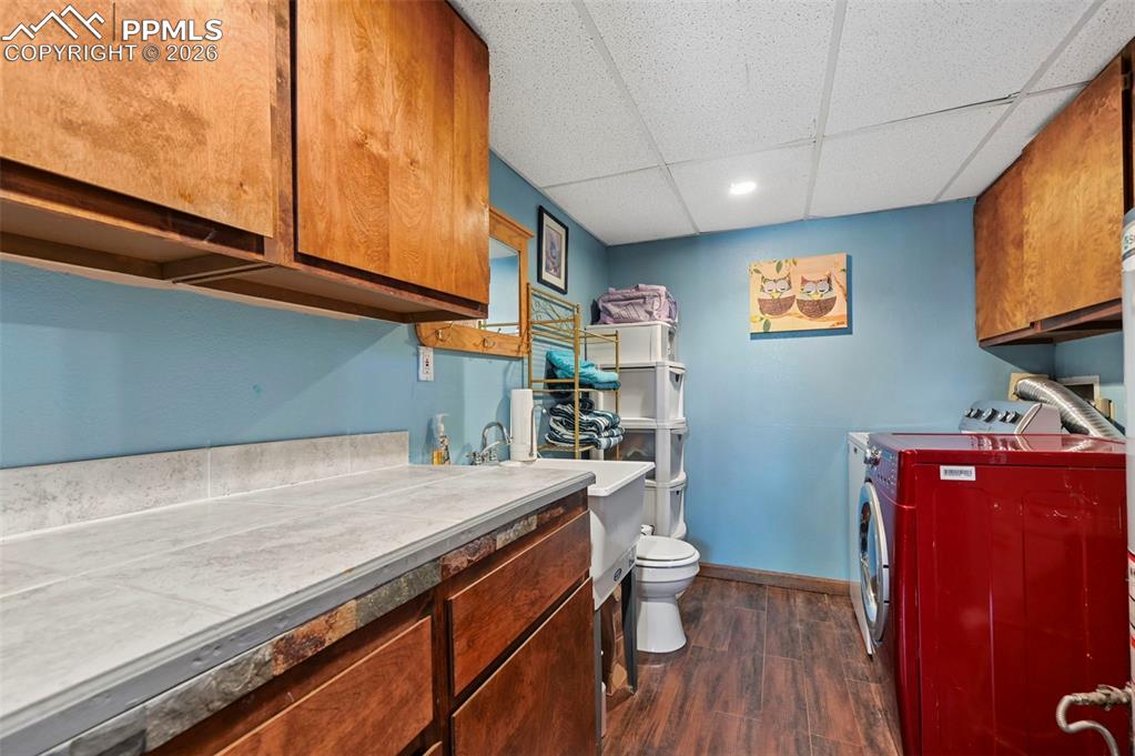Image 17 of 27: This utility space features wood cabinetry, a light-colored countertop, and