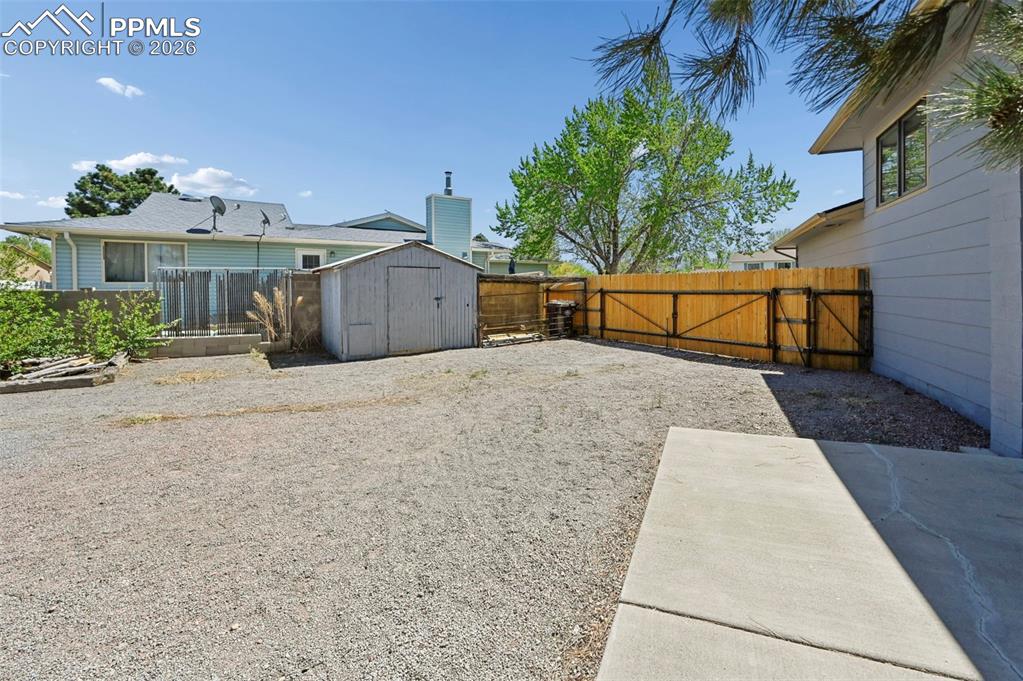 Image 19 of 27: The property features an extensive gravel yard, a wooden fence, and a stora