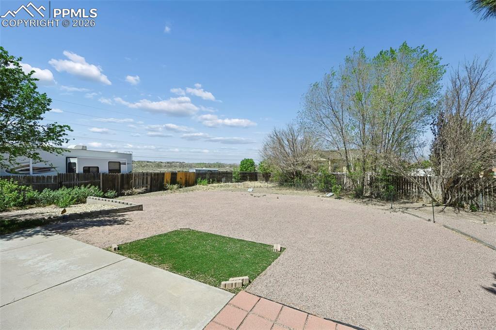 Image 22 of 27: This property features a spacious yard with a gravel surface, a defined pat