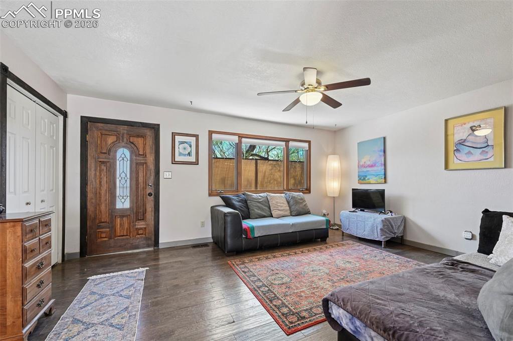 Image 4 of 27: The living area features wood flooring, a decorative entry door with a lead