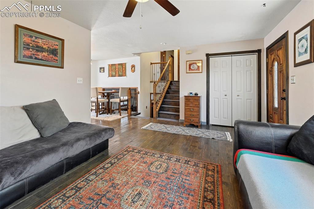 Image 7 of 27: The living area features hardwood floors and a ceiling fan, with a dining a