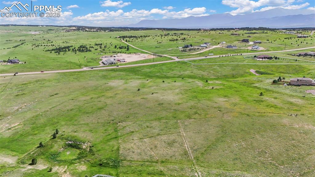 Image 5 of 23: Aerial view of the land with a mountain backdrop and agricultural land