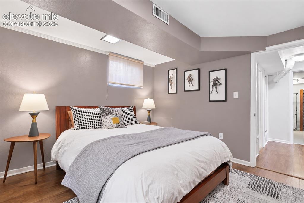 Image 21 of 36: Charming lower-level bedroom featuring a built-in original wood dresser tha