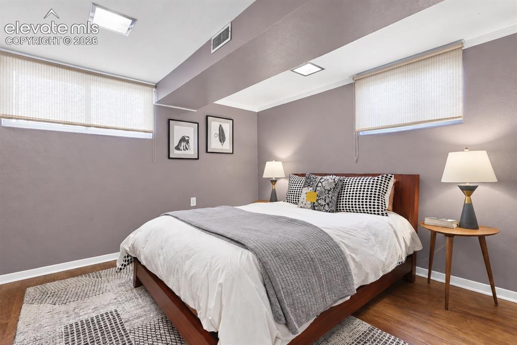 Image 22 of 36: Charming lower-level bedroom featuring a built-in original wood dresser tha