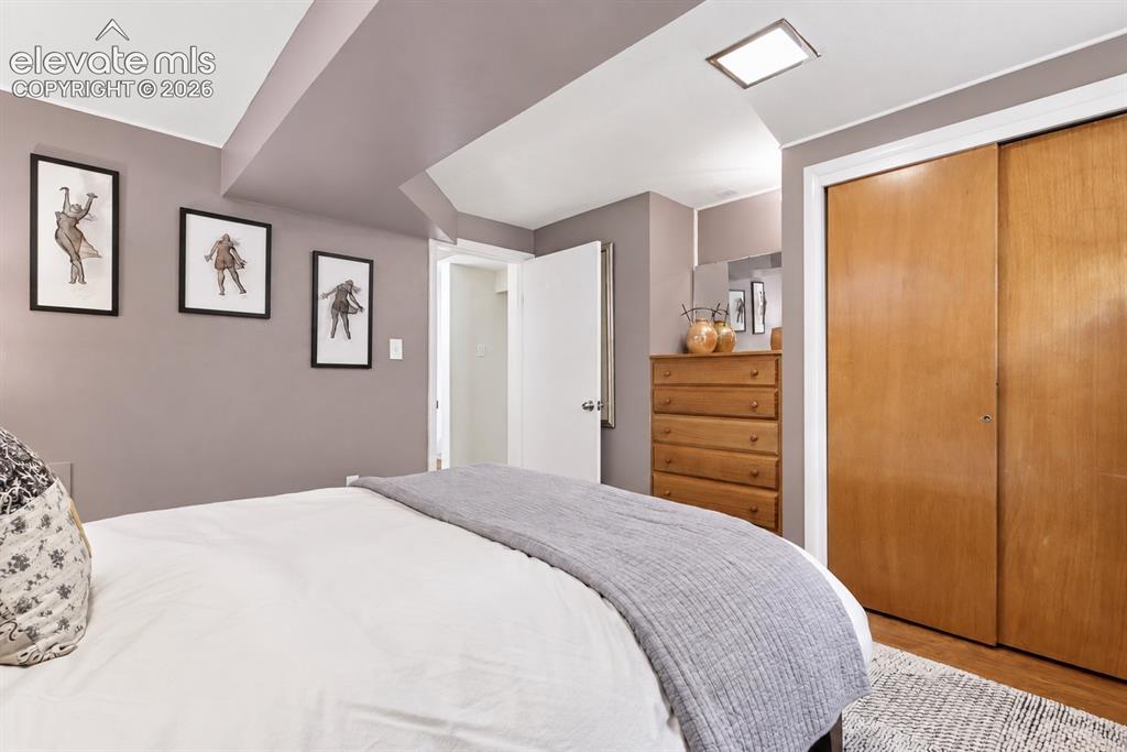 Image 23 of 36: Charming lower-level bedroom featuring a built-in original wood dresser tha
