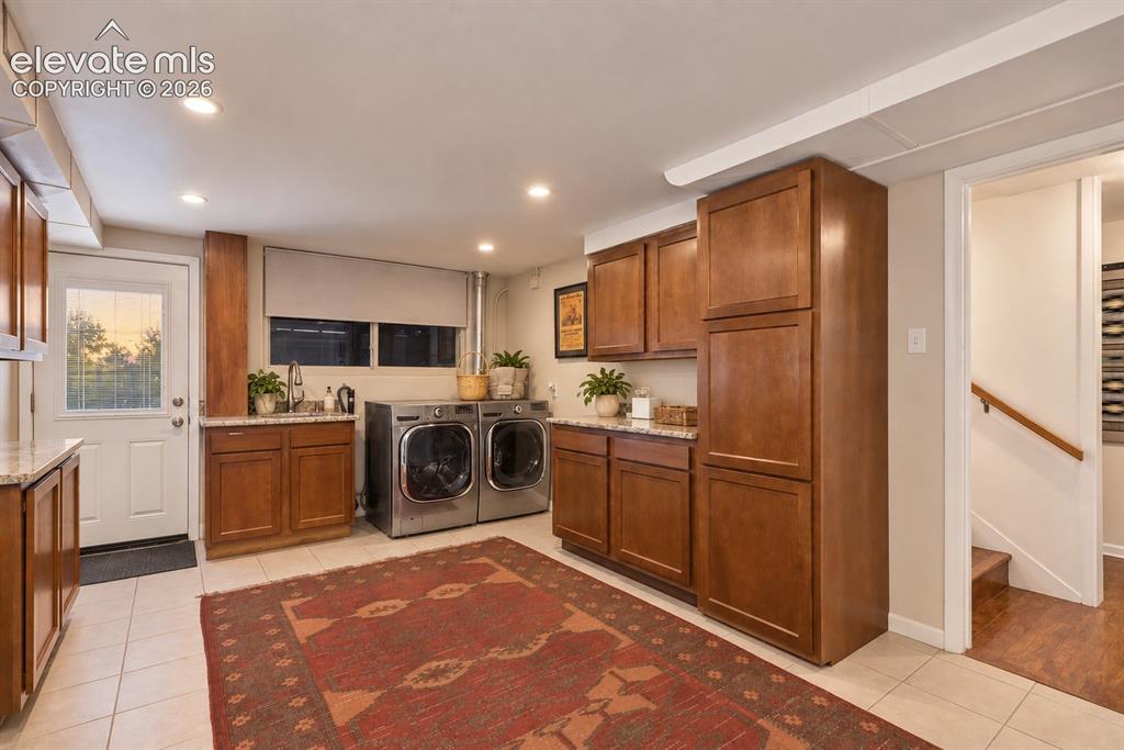 Image 28 of 36: Exceptional laundry room with utility sink, abundant cabinetry, stone count