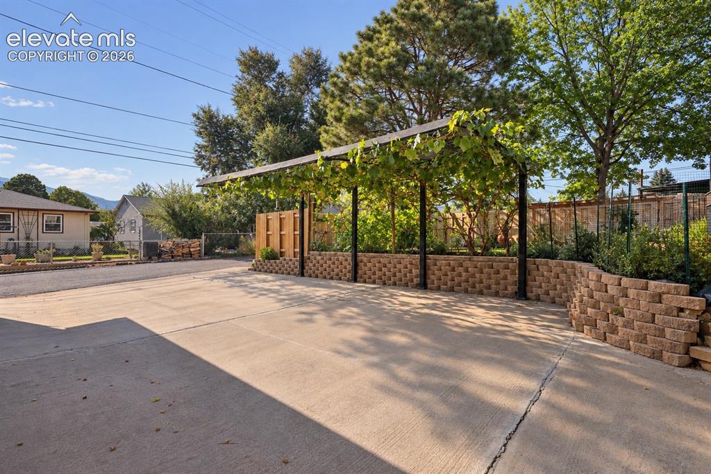 Image 33 of 36: Charming covered parking framed by mature grapevines, adding character and 
