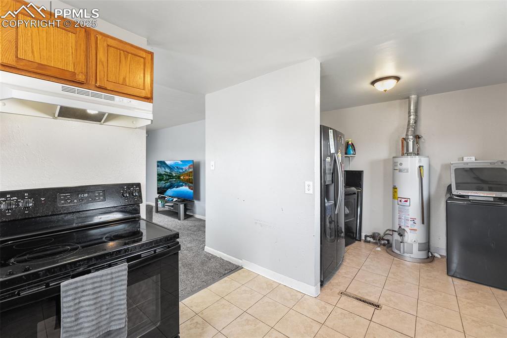 Image 7 of 24: Kitchen featuring black range with electric stovetop, gas water heater, und