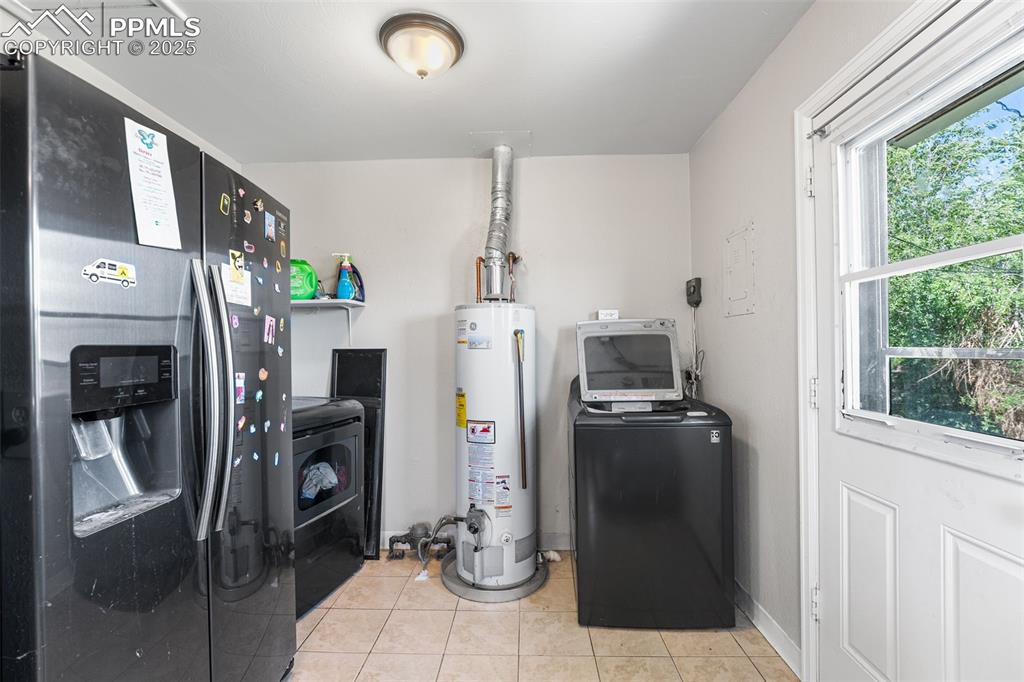 Image 8 of 24: Washroom featuring gas water heater, washing machine and clothes dryer, and