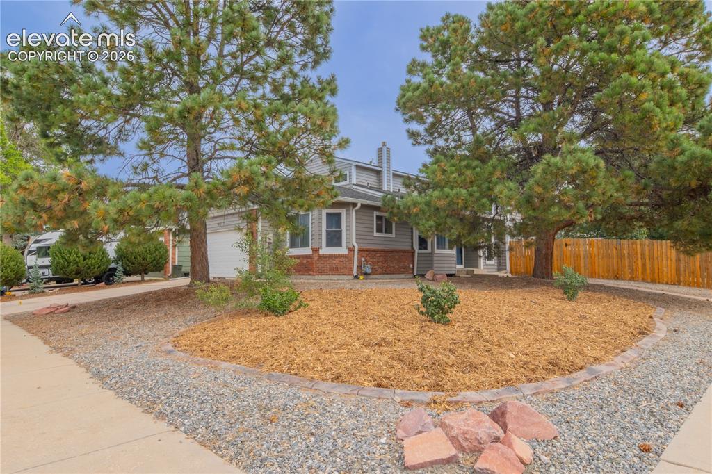 Image 1 of 42: Siding exterior with brick accents, attached garage, and a wood privacy fen