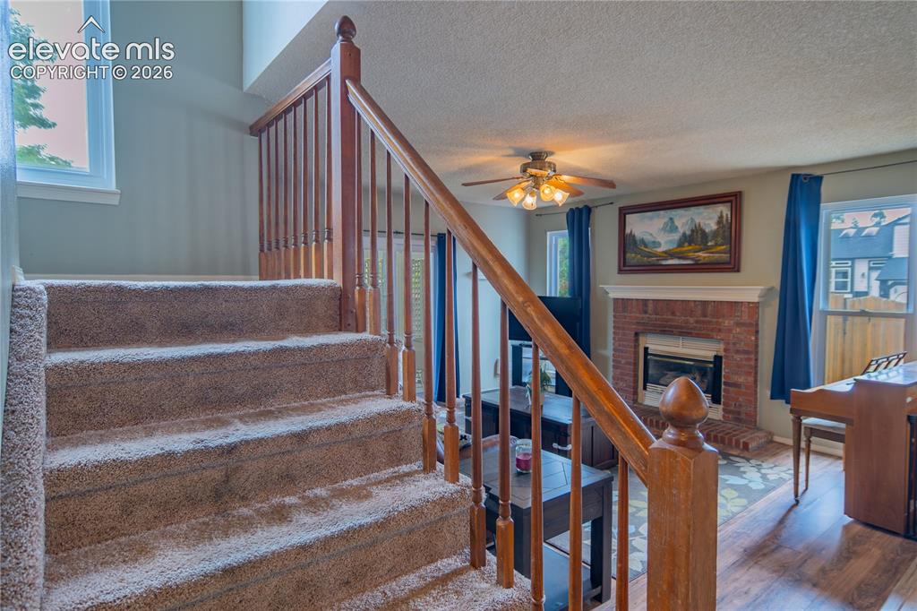 Image 16 of 42: Carpeted staircase with wood railing, leading to a living area featuring a