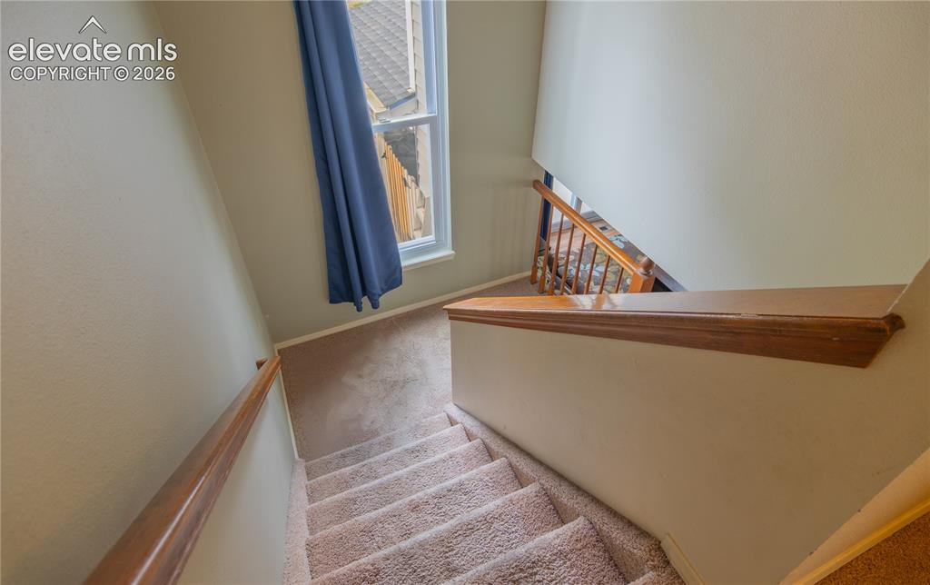Image 17 of 42: Carpeted staircase with wood-finish handrails and banister