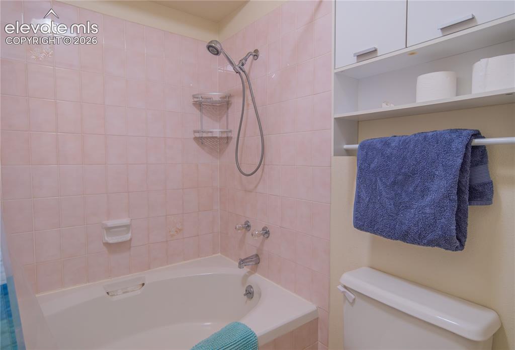 Image 19 of 42: Built-in white bathtub with a shower fixture