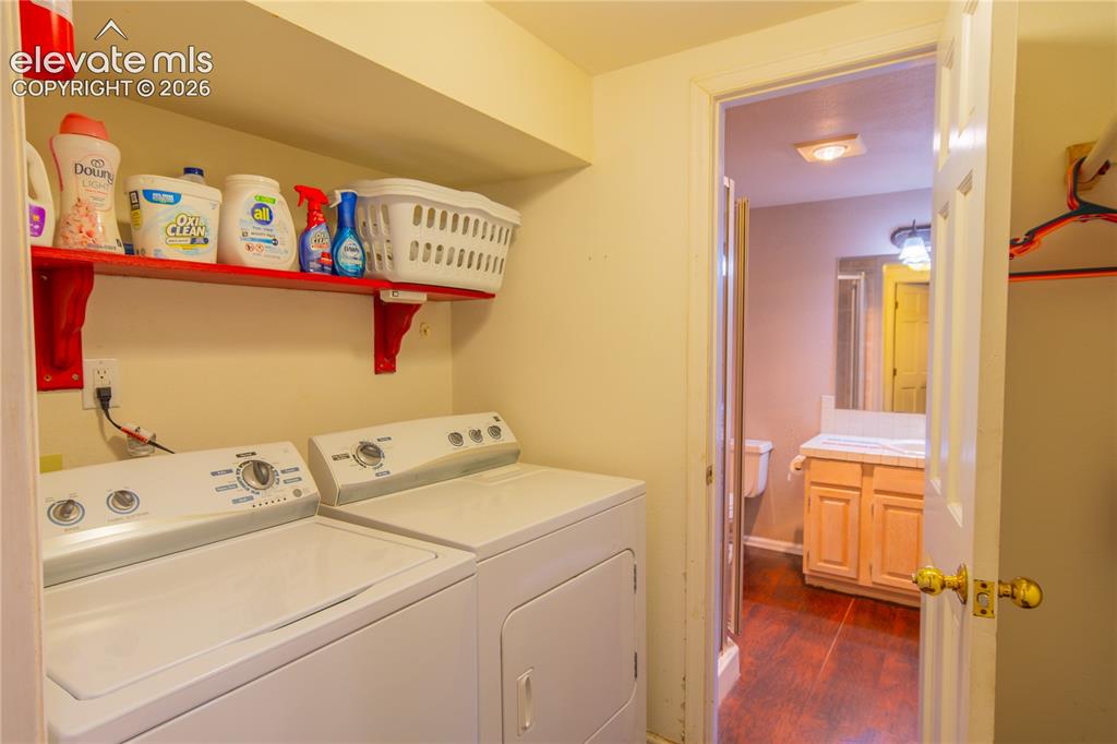 Image 26 of 42: In-unit laundry appliances, built-in shelving, wood-finish flooring in bath