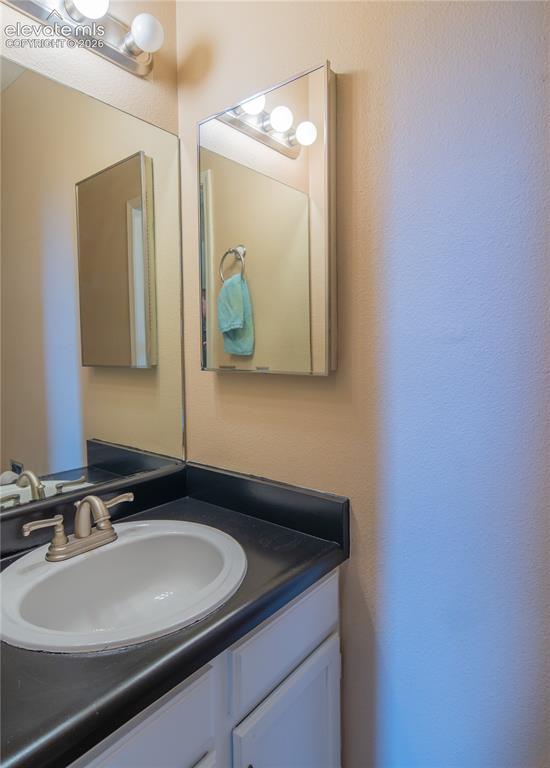 Image 27 of 42: White vanity with dark countertop, undermount sink, and brushed nickel fauc
