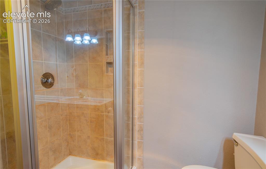 Image 30 of 42: Glass-enclosed shower featuring a tiled surround, built-in shelving, and a 