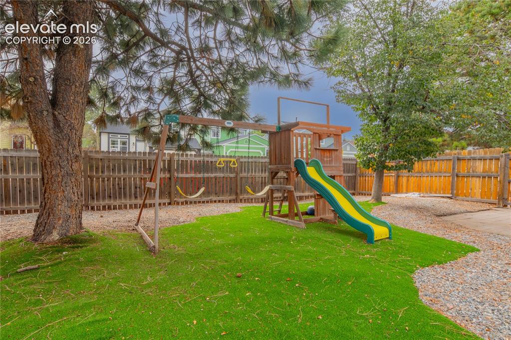 Image 36 of 42: Enclosed backyard featuring artificial turf, mature trees, a wooden privacy