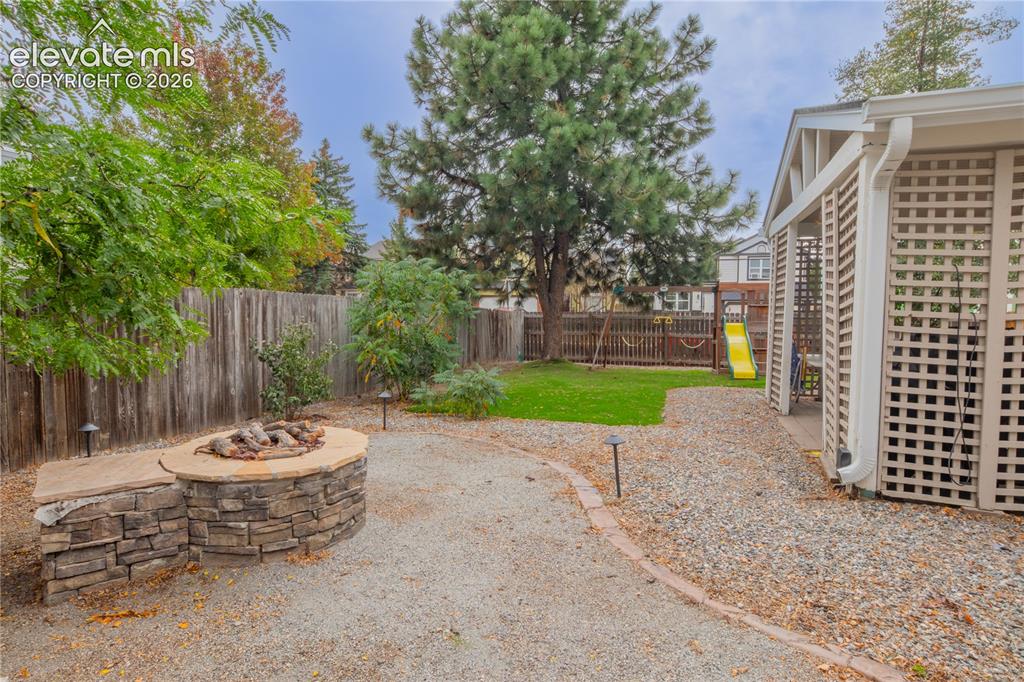 Image 39 of 42: Backyard featuring a stone-clad fire pit with an integrated stone bench, gr