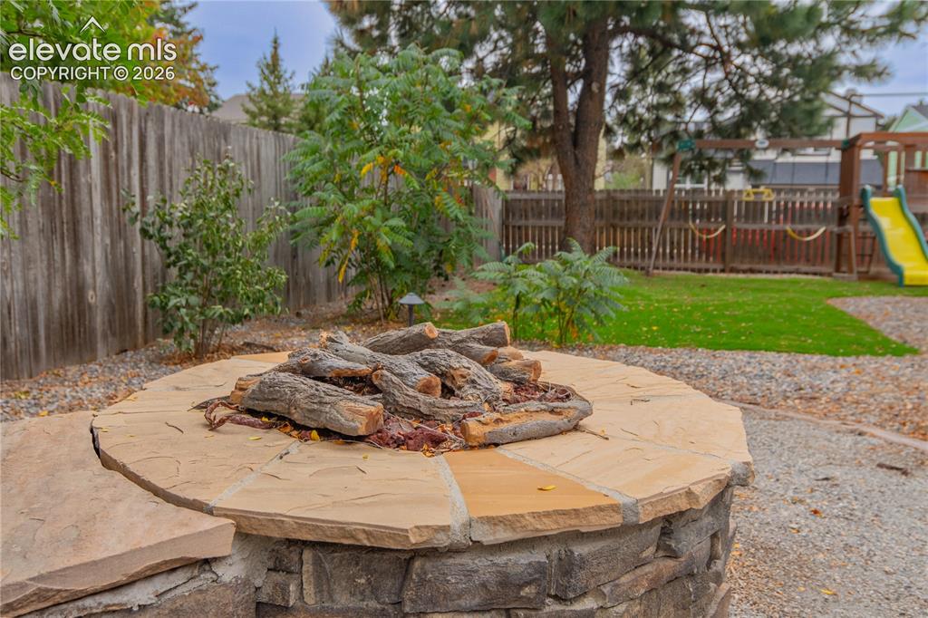 Image 40 of 42: Stone fire pit with flagstone capping, gravel surround, and wood privacy fe