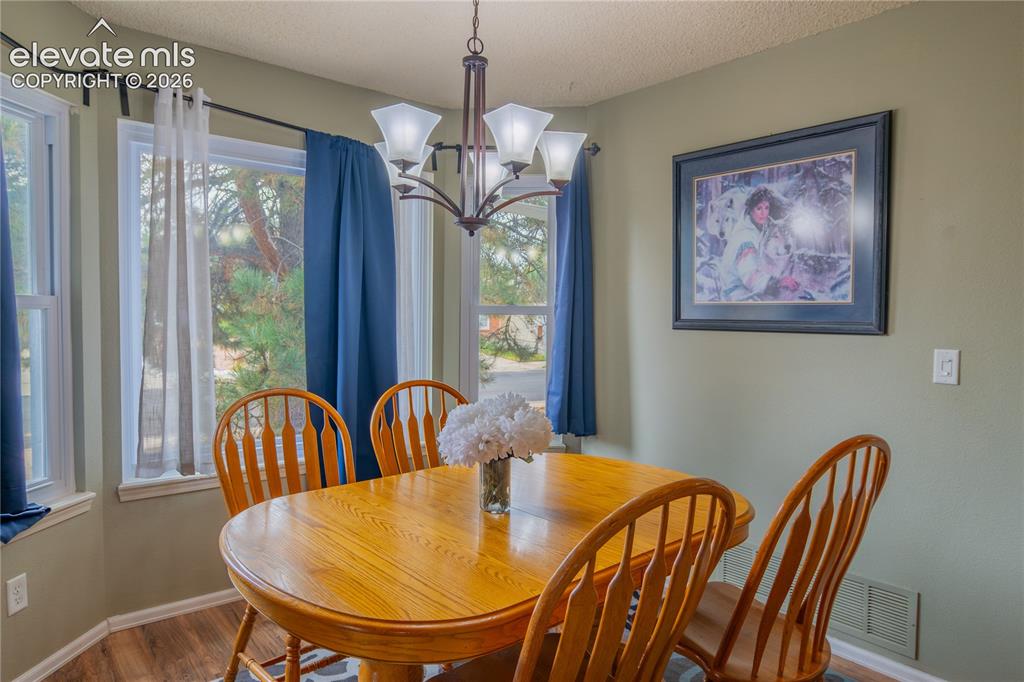 Image 8 of 42: Bay window, wood-finish flooring, recessed lighting, chandelier, neutral wa