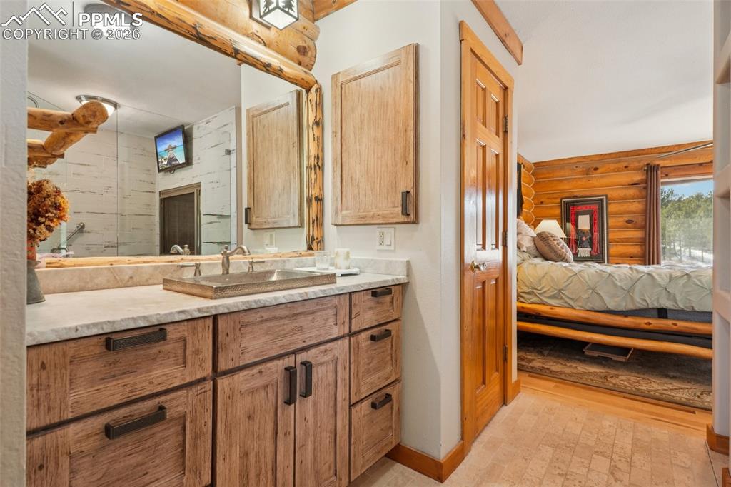 Image 12 of 40: Ensuite bathroom with rustic walls, vanities and tile flooring