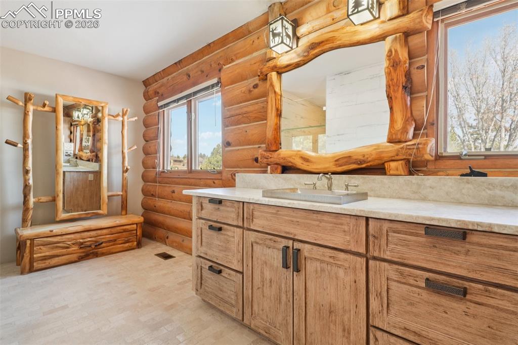 Image 14 of 40: Bathroom with rustic walls, vanity, and tile floors