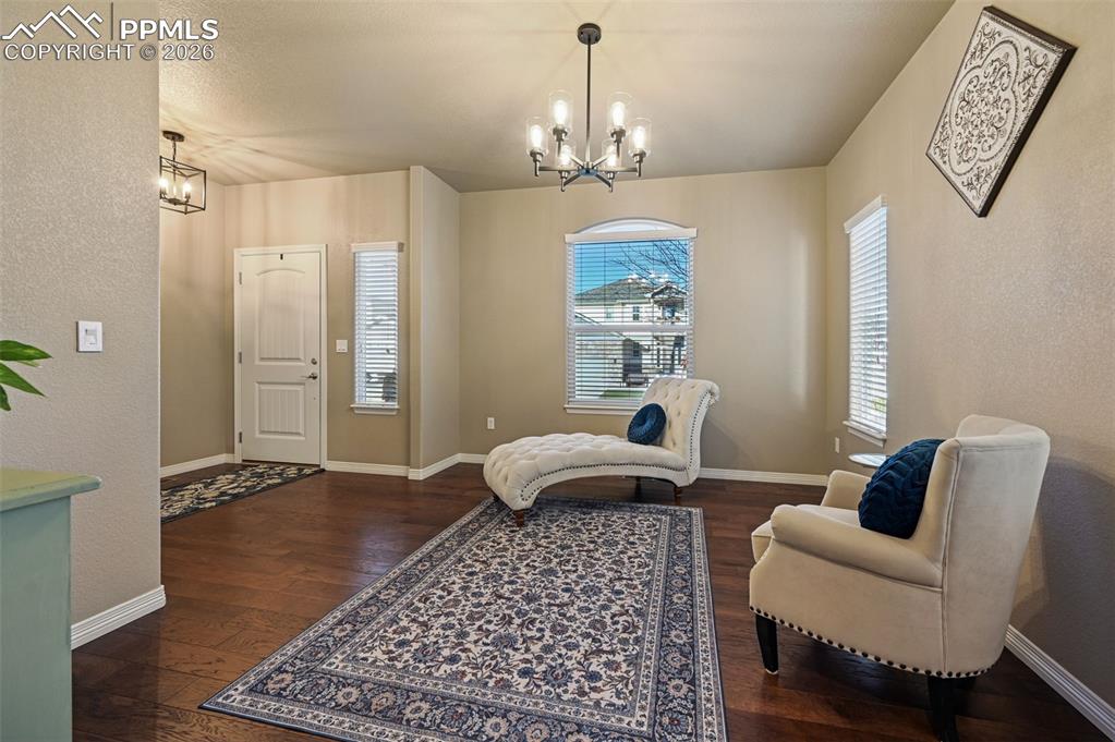 Image 10 of 38: Sitting room featuring dark wood-style flooring, a chandelier, and a textur