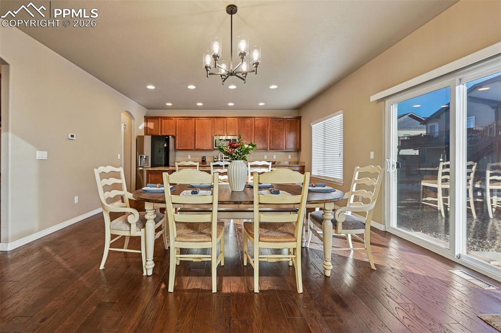 Image 13 of 38: Dining room with arched walkways, dark wood-style floors, and a chandelier