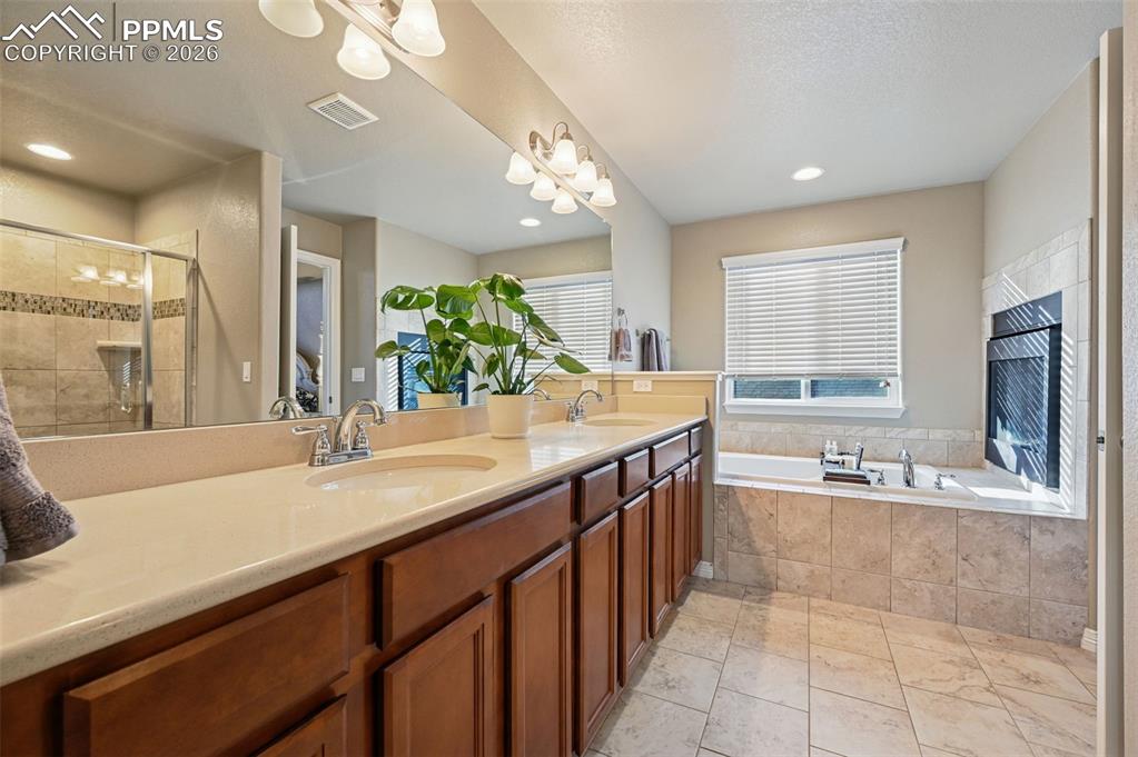 Image 25 of 38: Full bath with a stall shower, double vanity, and a garden tub