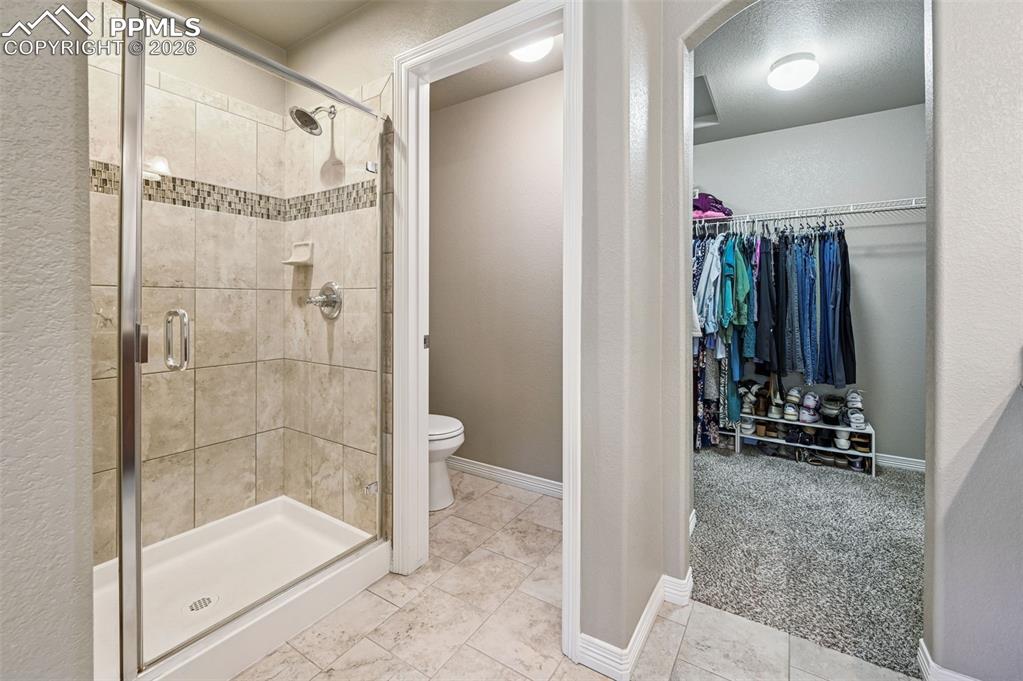 Image 26 of 38: Full bathroom with light carpet, a walk in closet, and a shower stall